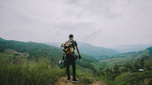 Rear view of man looking at mountain against sky