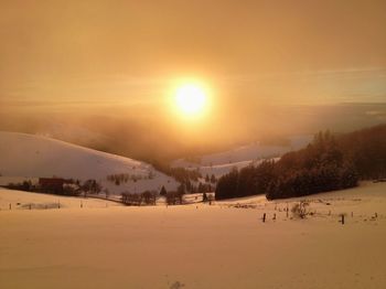 Scenic view of snow covered landscape against sky during sunset