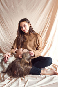 Sisters having fun on beige color textile background