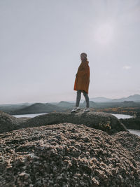 Full length of man standing on rock against sky