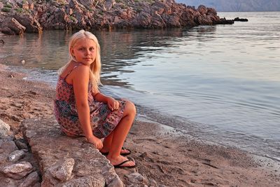 Portrait of woman sitting on rock at beach