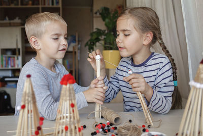 Cute sibling playing with christmas ornaments at home