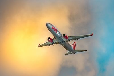 Low angle view of airplane flying against sky during sunset