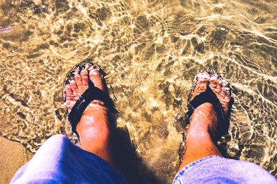 Low section of man wearing shoes on beach