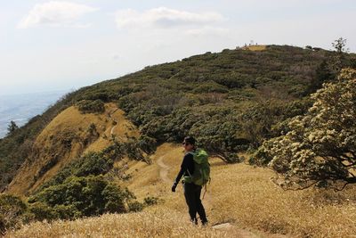 Rear view of man standing on mountain against sky