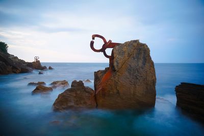 Scenic view of rocks on beach against sky