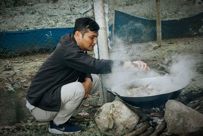 Side view of man preparing food on barbecue grill