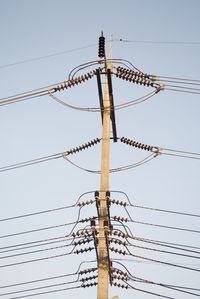 Low angle view of electricity pylon against clear sky