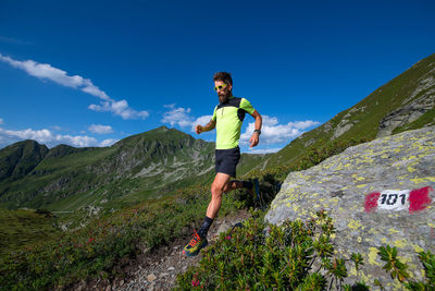 Male athlete practicing mountain running on a trail downhill.