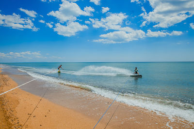 People surfing in sea against sky during sunny day
