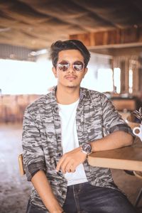 Portrait of young man wearing sunglasses sitting in cafe