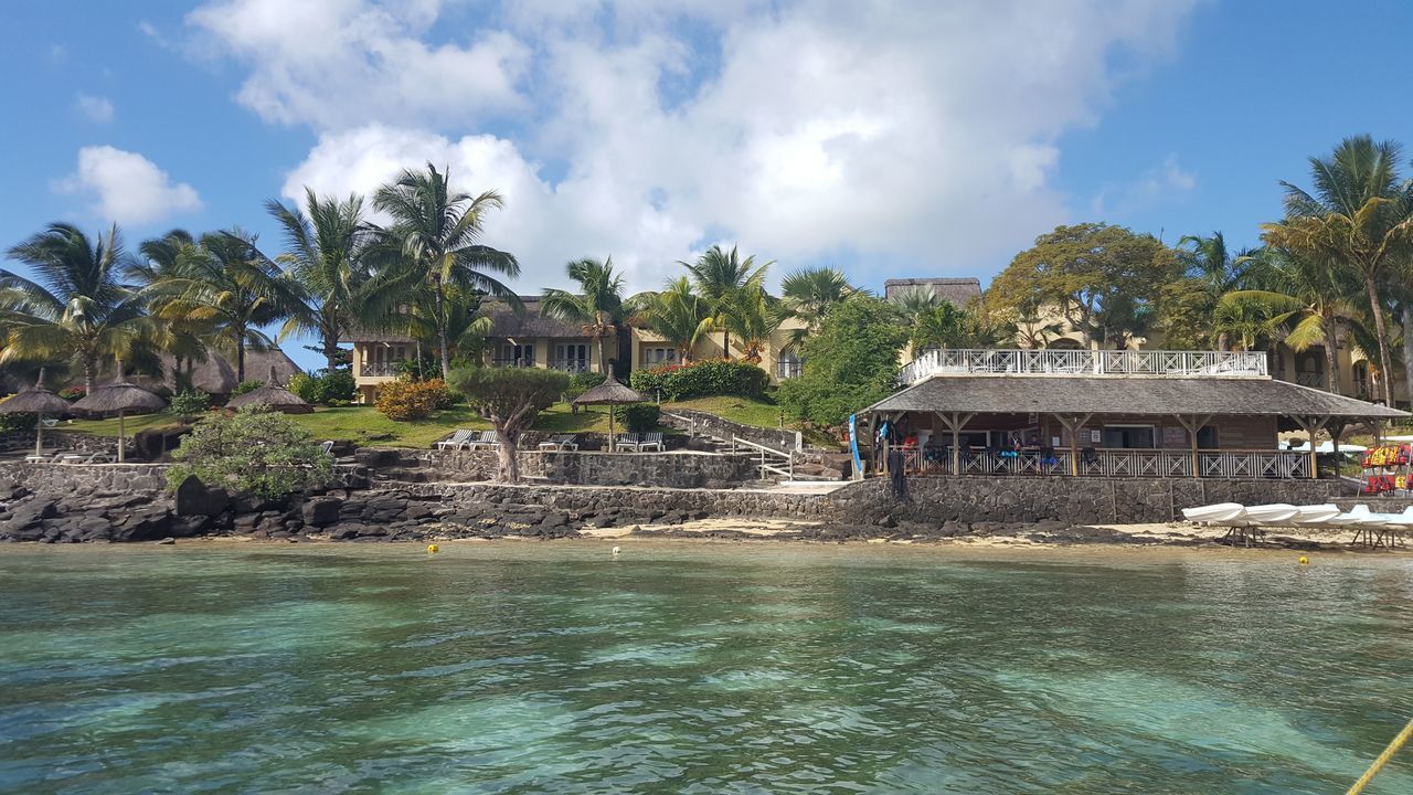 architecture, built structure, building exterior, water, tree, sky, waterfront, cloud - sky, fountain, cloud, travel destinations, place of worship, palm tree, day, house, religion, tourism, pond, outdoors, incidental people