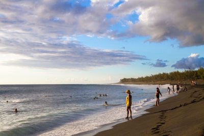 People enjoying on sea shore against sky