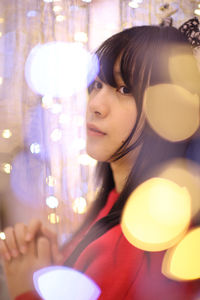 Close-up of young woman holding illuminated string lights