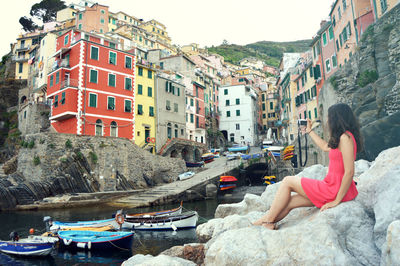Young woman sitting on rocks against buildings in city