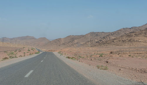 Road leading towards mountains against sky