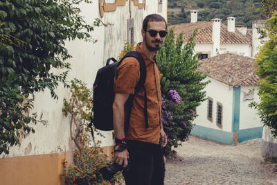 Young man standing by plants in city