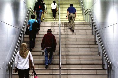 Rear view of people walking on escalator