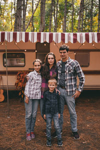 Happy family on camping trip relaxing in the autumn forest camper trailer fall season outdoors trip