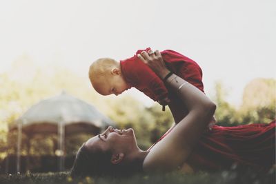 Side view of young woman lying down against sky