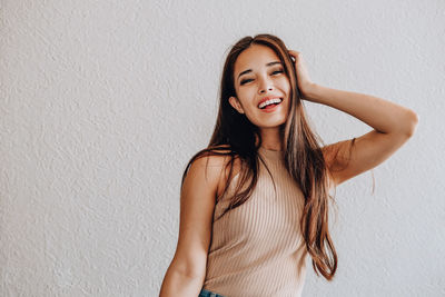 Portrait of beautiful young woman standing against wall