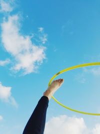 Low angle view of woman with hula hoop against blue sky