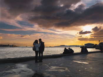 Women on beach against sky during sunset