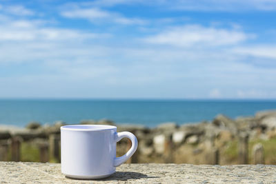 Empty white cup on blurred beach background. copy space