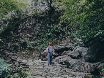 Woman walking and standing by rocks in forest