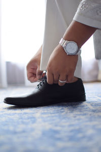 Low section of woman tying shoelace on hardwood floor