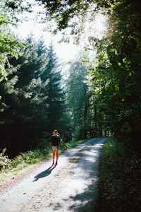 Rear view of woman walking on road amidst trees