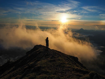 Silhouette woman standing on a mountain against sky in the morning.