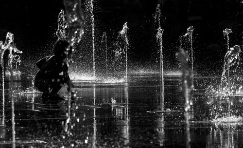 Man splashing water in fountain at night