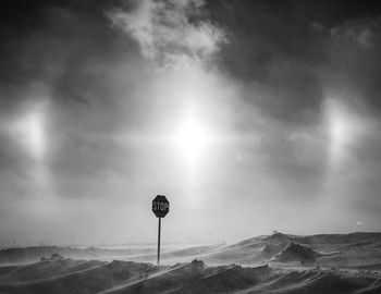 Stop sign on road overblown by snow, atmospheric sundogs overhead