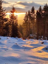 Snow covered landscape against sky during sunset