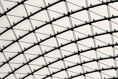 Low angle view of metal ceiling glass against sky in black and white