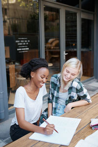 Smiling female friends studying at college campus