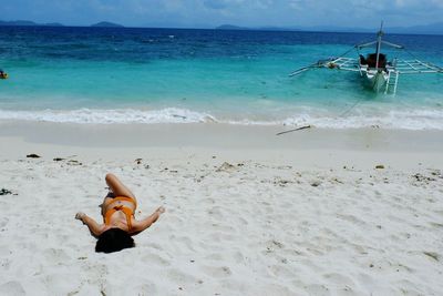 Man lying down on beach against sky