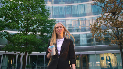 Portrait of young woman standing against trees