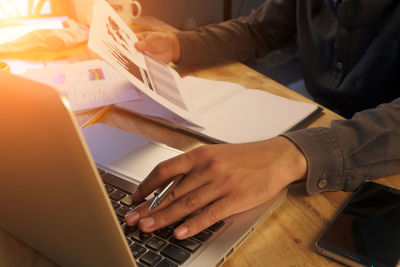 Midsection of woman using laptop on table