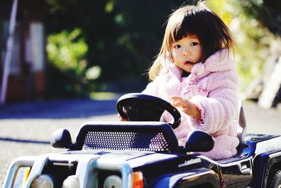 Portrait of cute girl sitting on toy car