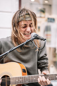 Young rocker singing with angry expression and playing a guitar in the street