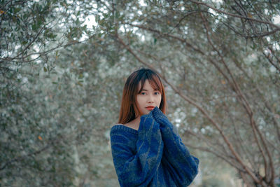 Portrait of woman standing against tree during winter