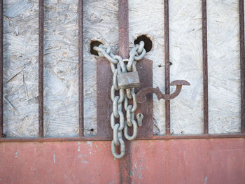 Close-up of rusty chain hanging on metal door