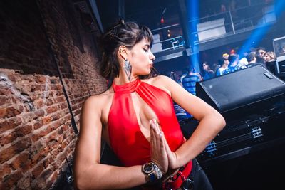 Young woman looking away while standing against wall