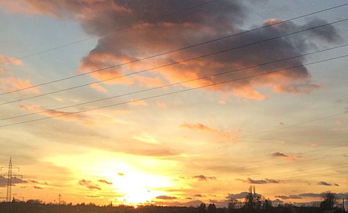 Low angle view of electricity pylon against cloudy sky