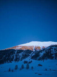 Scenic view of snow covered mountain against blue sky