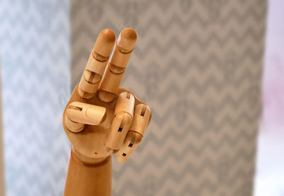 Close-up hand of wooden doll showing two fingers