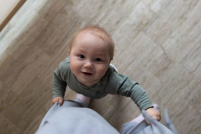 High angle view of cute baby boy sitting on hardwood floor