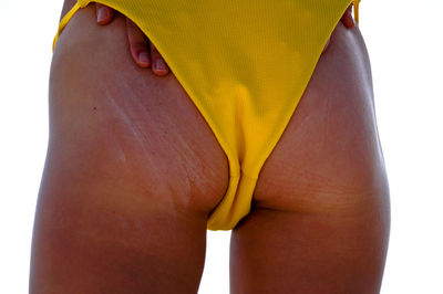 Midsection of woman wearing yellow bikini bottom